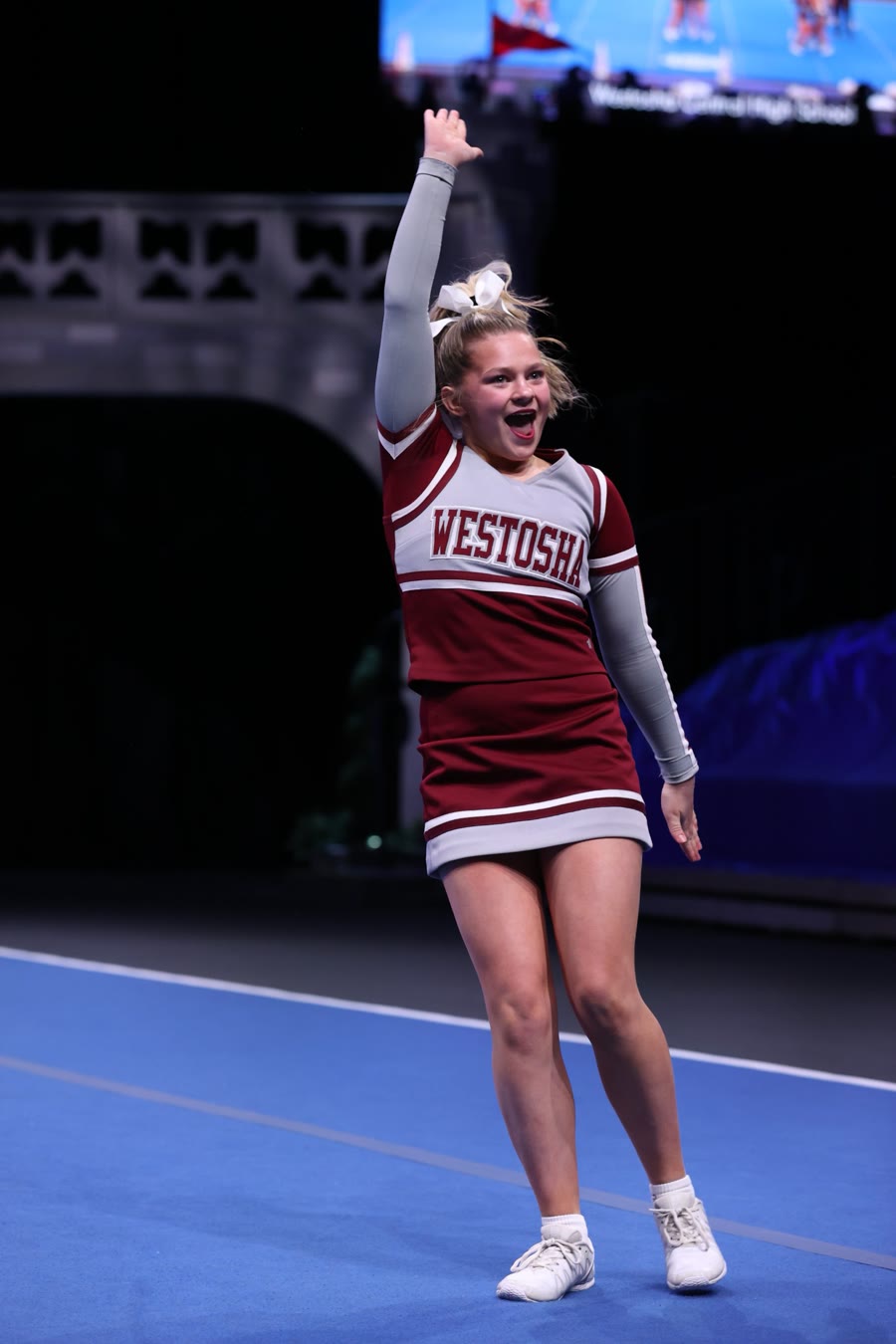 Ella cheering with her arm raised during a competition routine