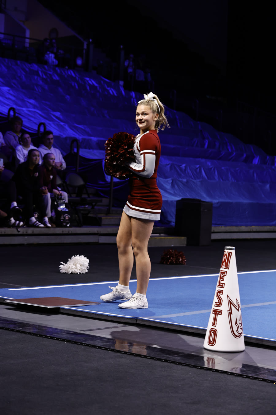 Ella smiling with pom poms on the competition mat