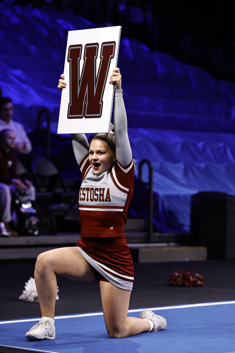 Ella holding a W sign above her head in a kneeling lunge