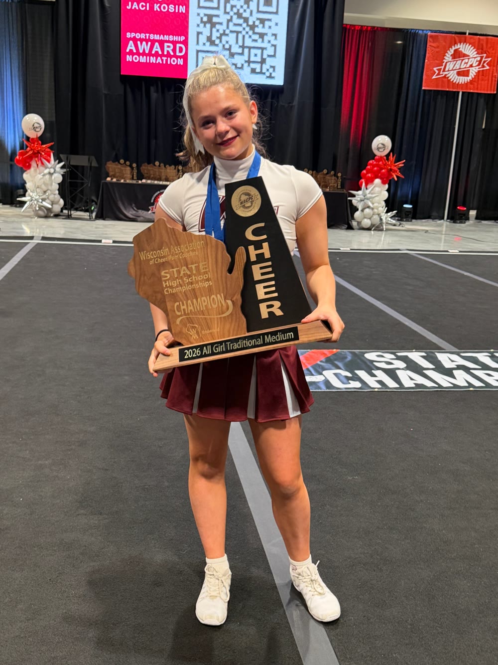 Ella holding the 2026 Wisconsin All Girl Traditional Medium state championship trophy