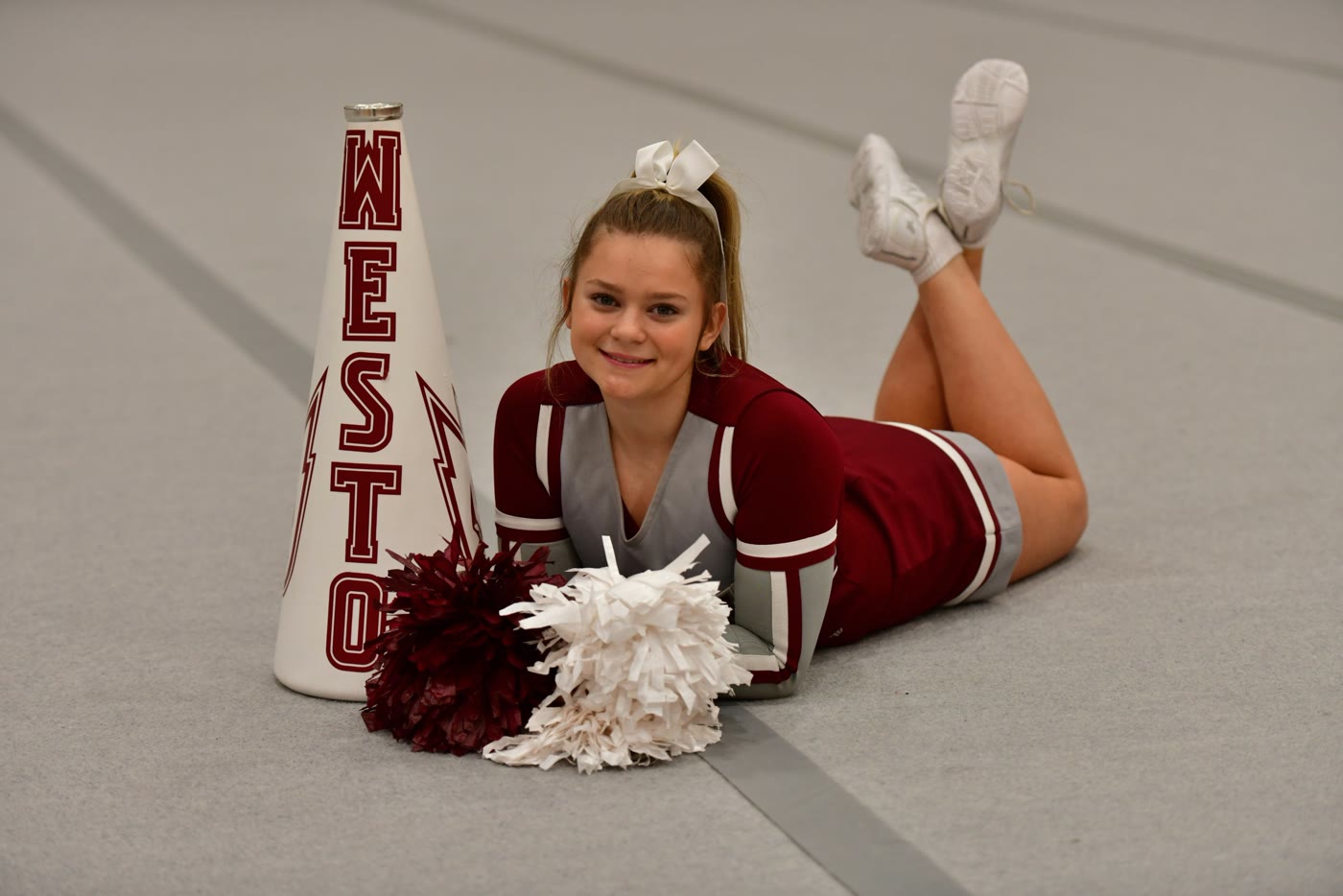 Ella in her Westosha uniform with pom poms and a megaphone